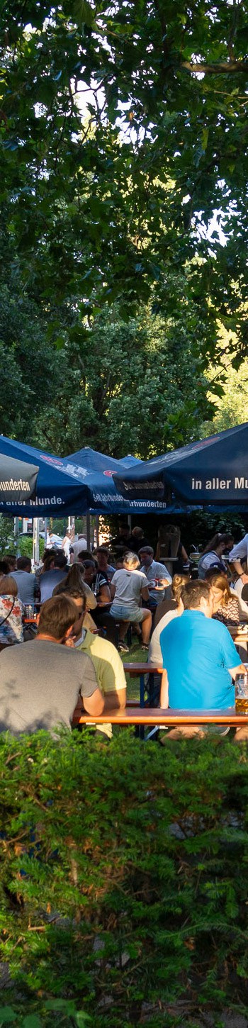 Gäste an Biertischen beim Public Viewing im Biergarten am Herstallturm